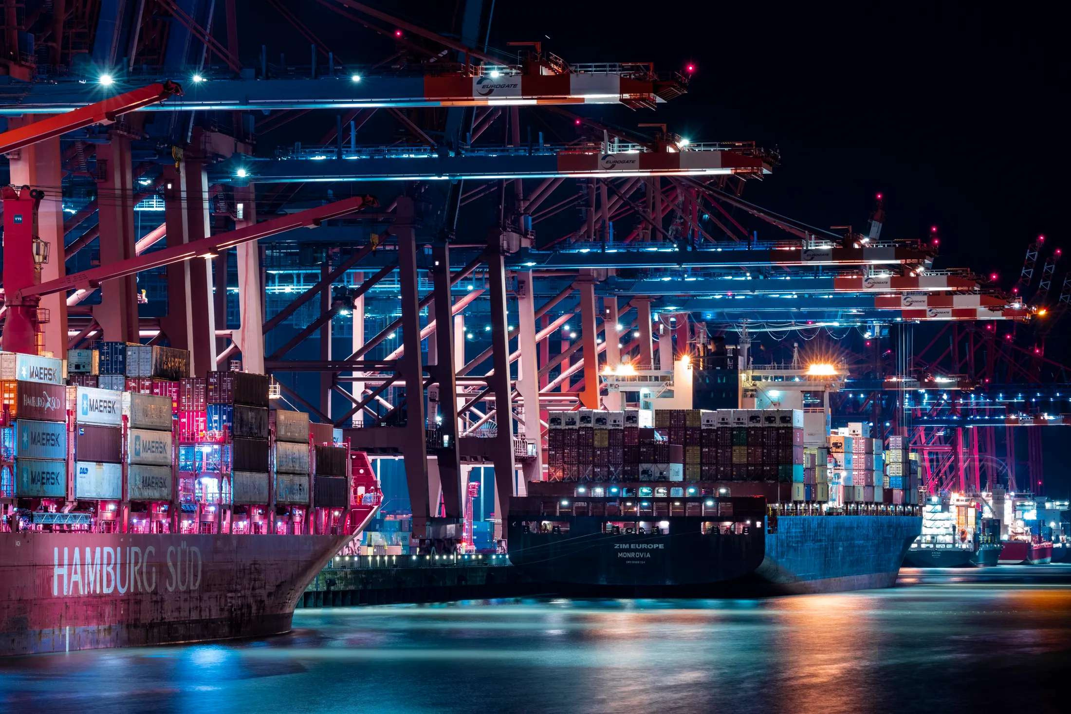 Stacked shipping containers in red, yellow, and blue against a clear sky
