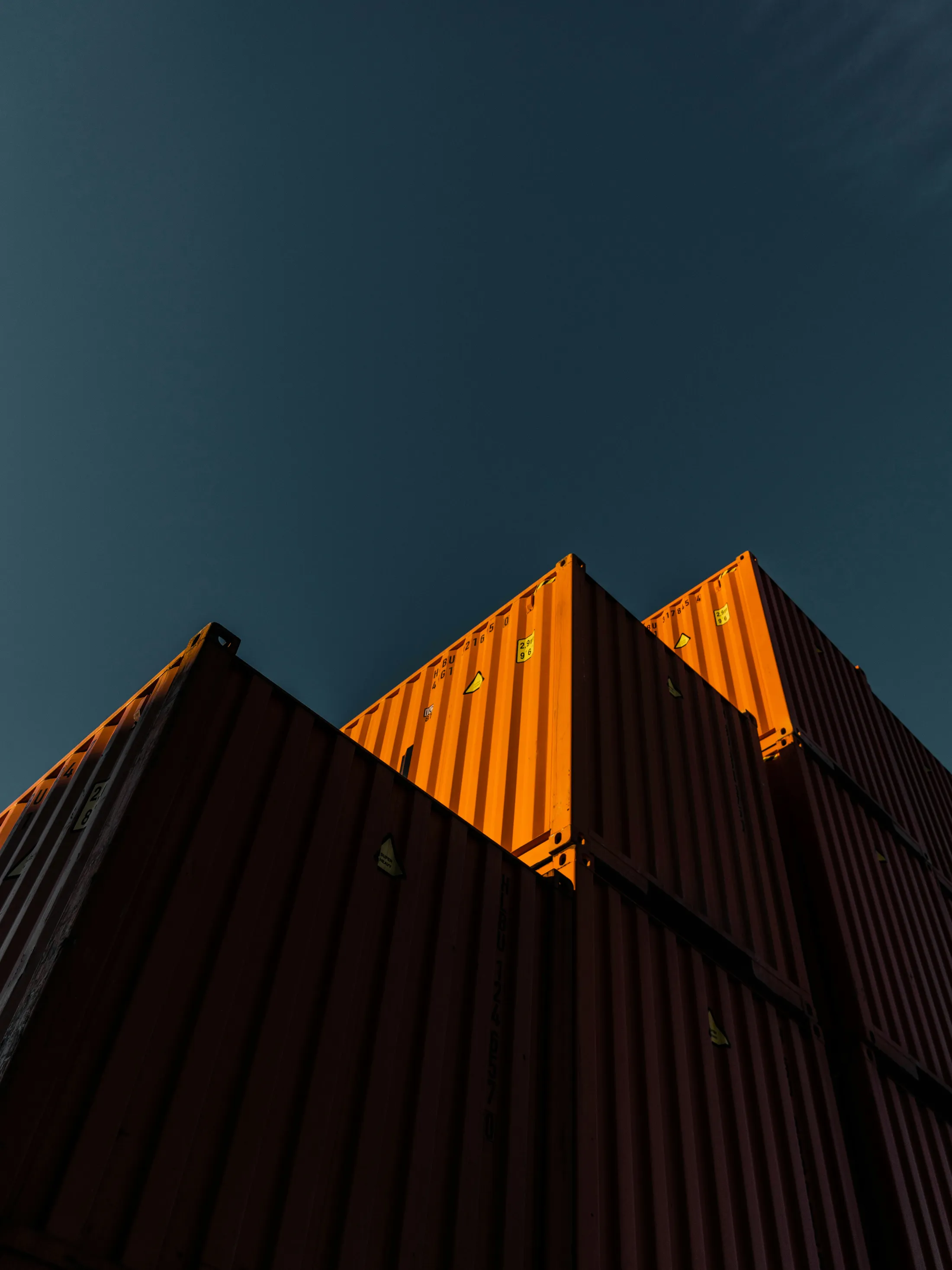Low-angle view of stacked orange shipping containers