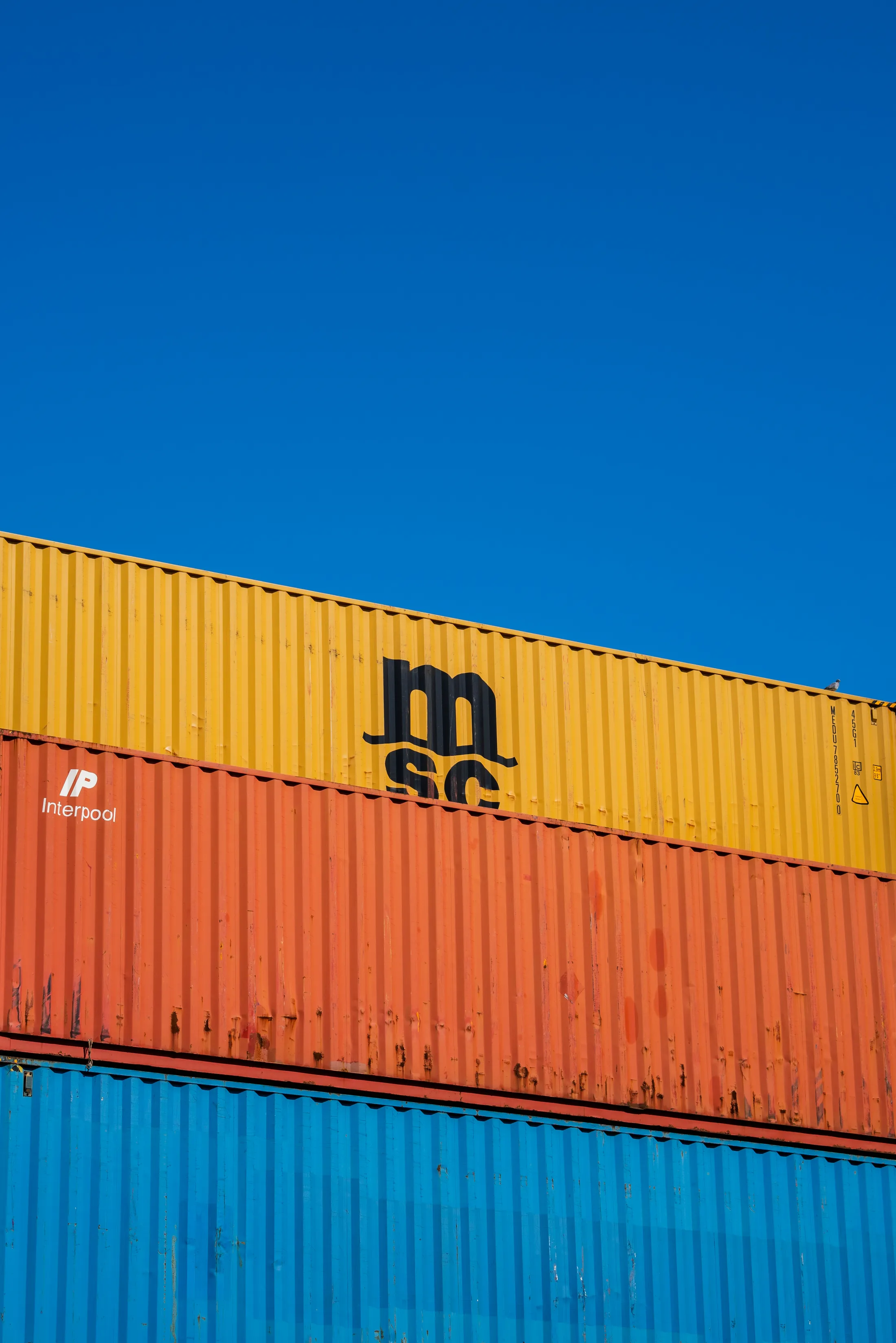Labeled shipping containers stacked in orange, yellow, and blue