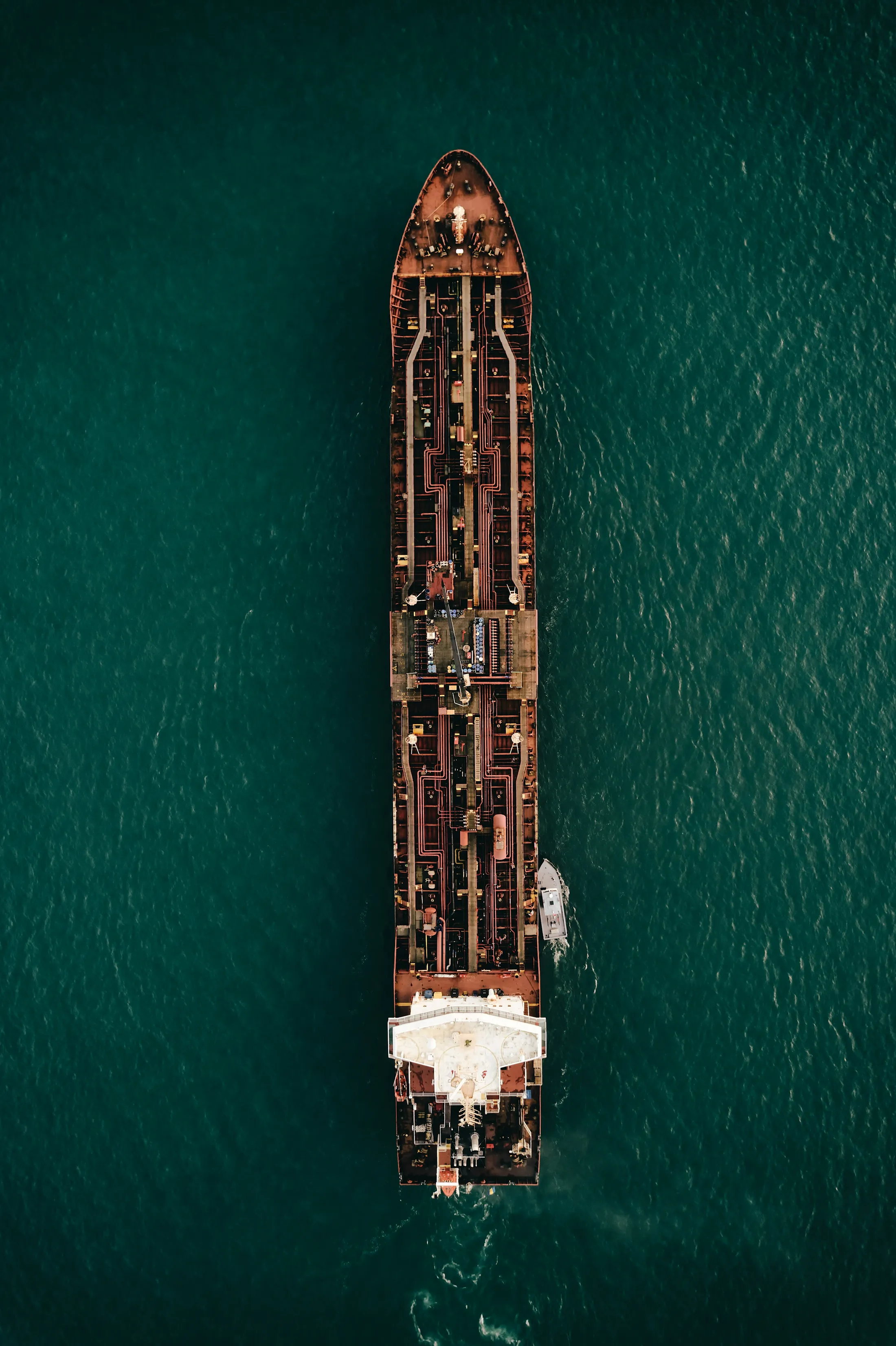 Aerial view of a cargo ship moving across dark green water
