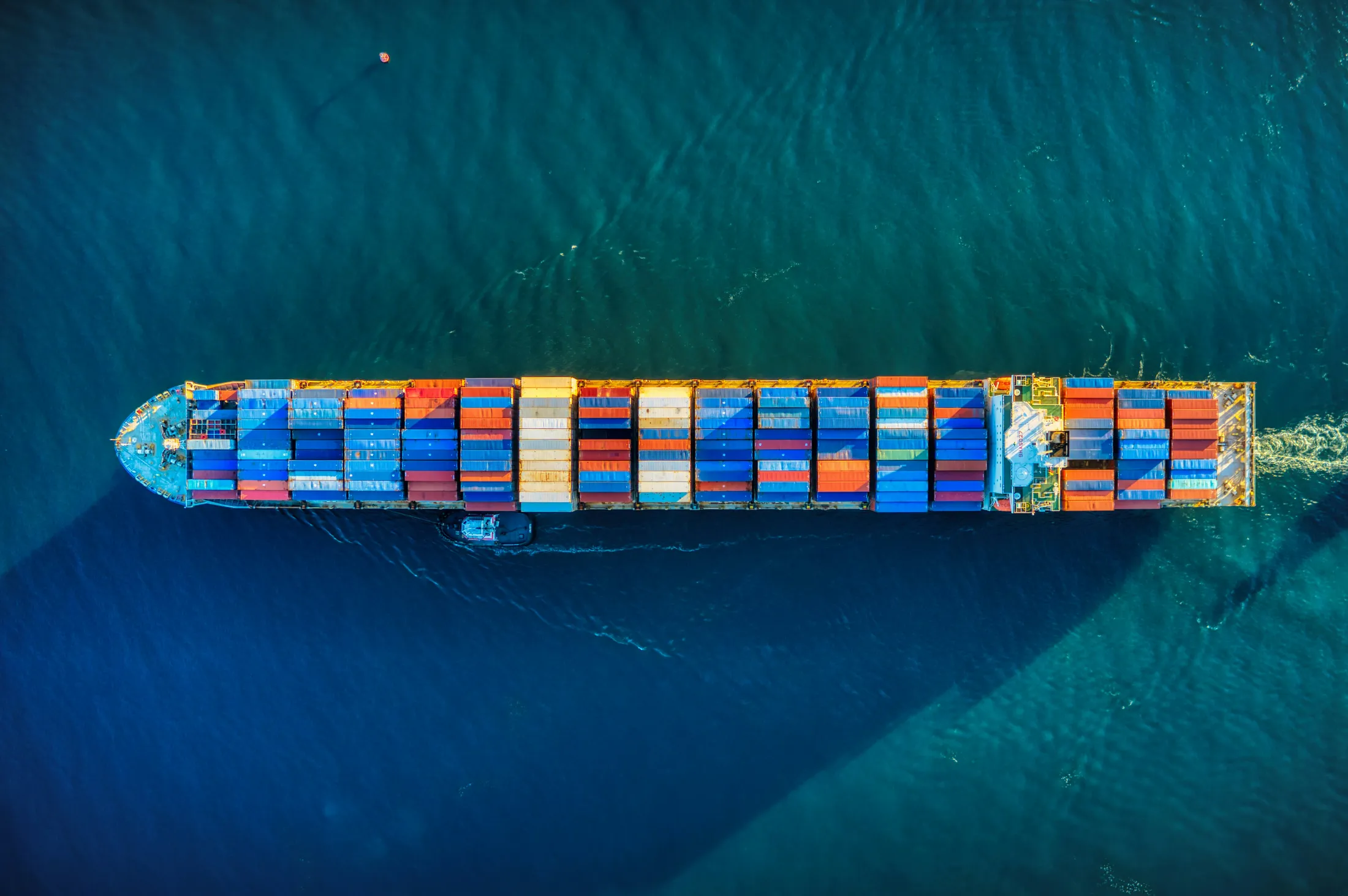 Aerial view of a loaded container ship escorted by a tugboat